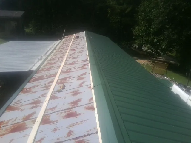 Old rusted panels beside newly installed green metal roofing — Wind Damage Roof Repair by Roofing Brothers in Rocky River