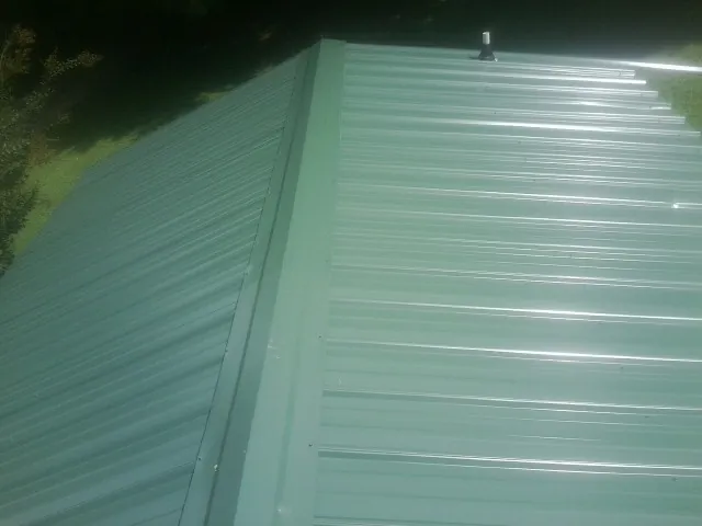 New green metal panels meeting at the ridge of a roof — Flat Roof Repair work by our crew in Rocky River