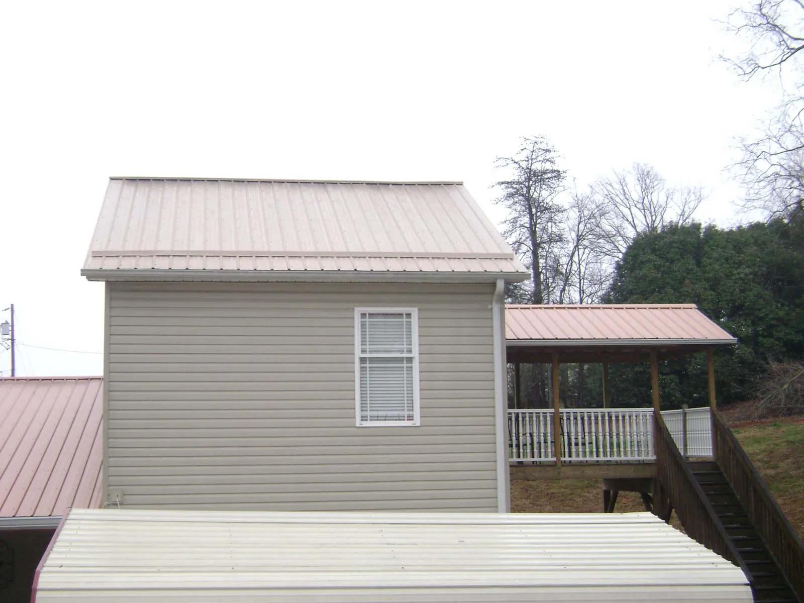 Tan metal roofs on a two story addition and attached porch, from a Roof Replacement job in Rocky River