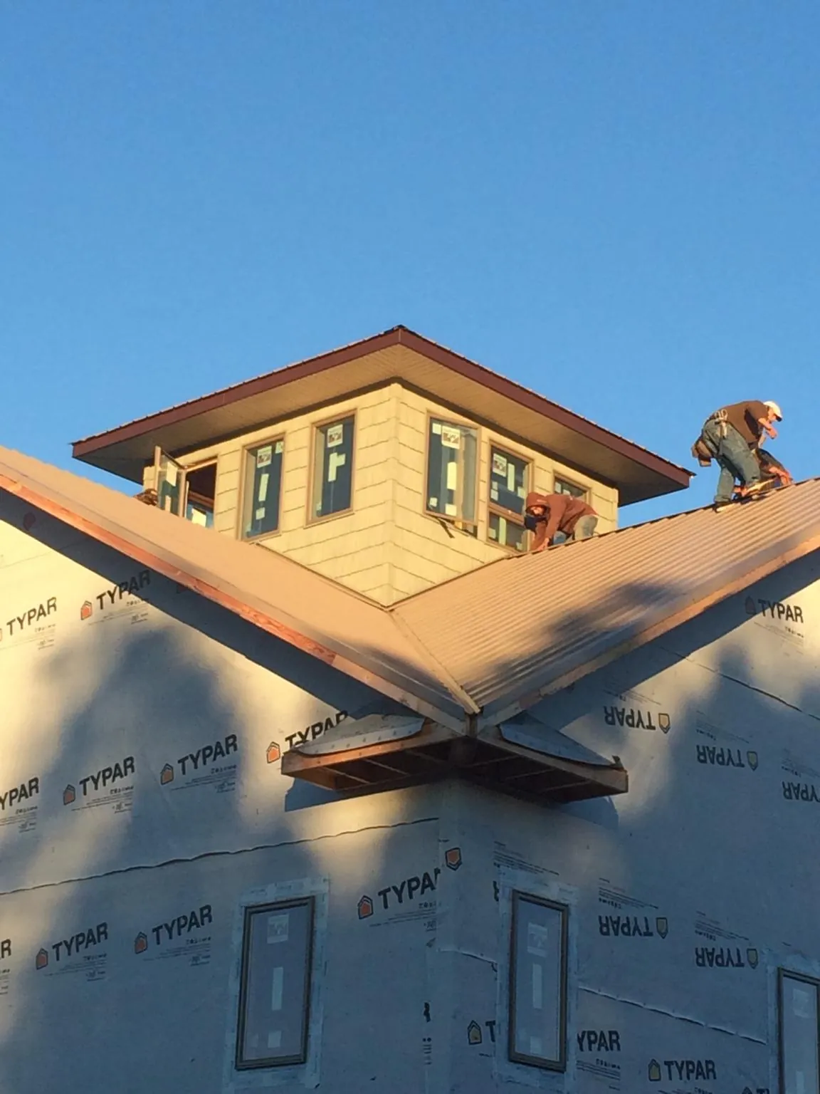 Roofers working around a rooftop cupola on a new metal roof at sunset — Roof Waterproofing in Rocky River by Roofing Brothers